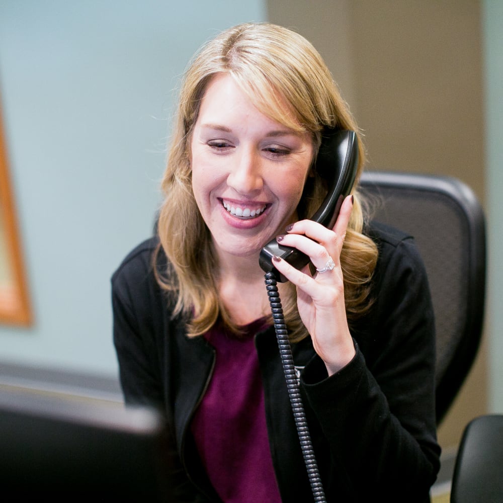 A receptionist on the North Seattle Orthodontics team is smiling while talking on the phone.
